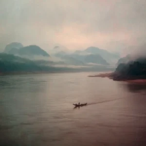 Misty mountains and a boat on the Mekong River in Luang Prabang