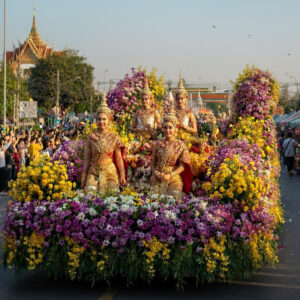 Flower Festival Chiang Mai float with women in traditional Thai dress surrounded by colorful flowers.