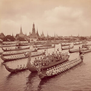 Traditional boats on Bangkok’s Chao Phraya River with Grand Palace in view