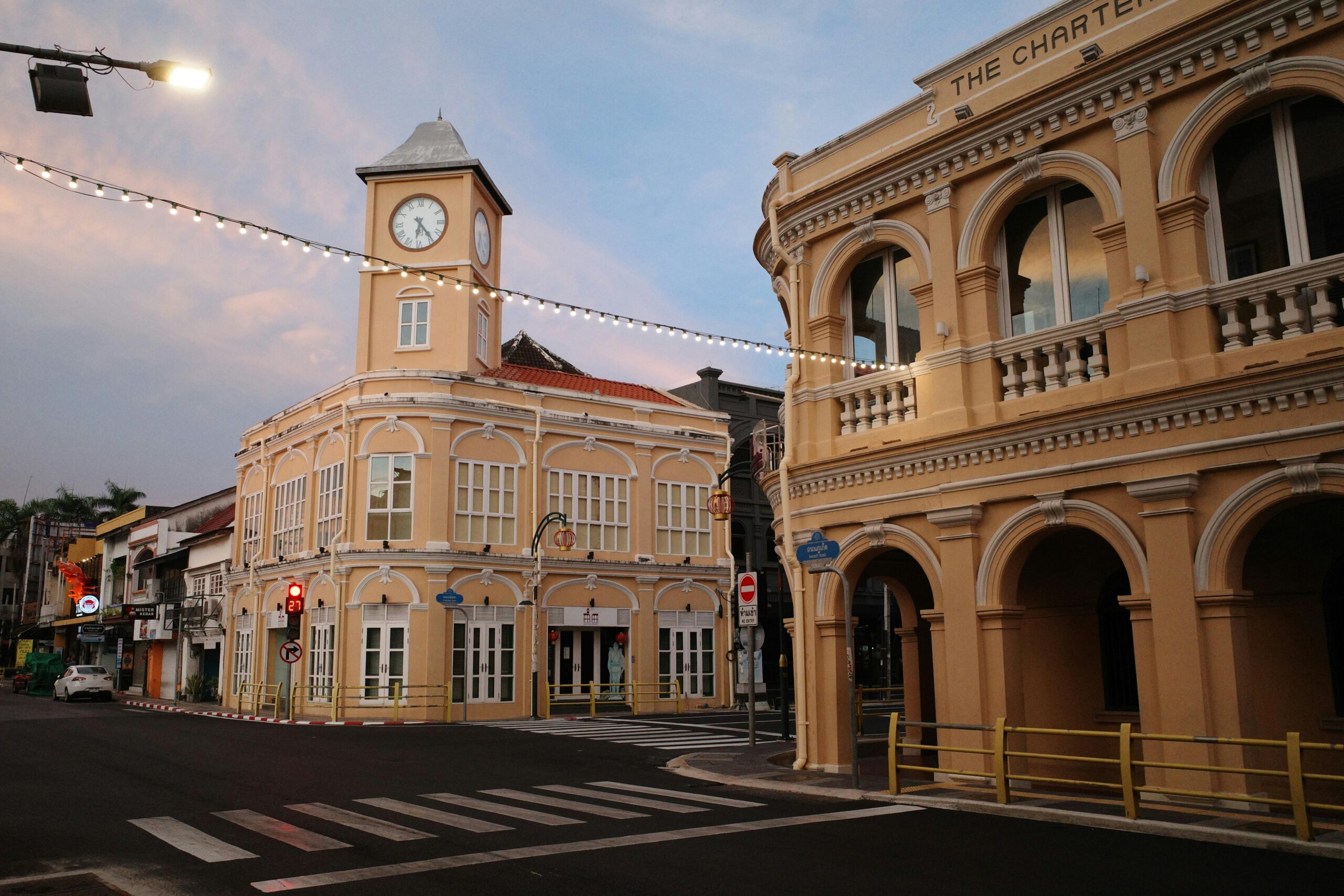 Phuket's historical Sino-Portuguese architecture: a clock tower and arched building at a quiet street corner.