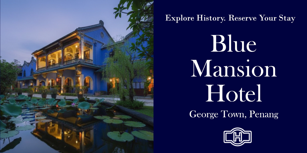 The Blue Mansion Penang reflecting in a serene pond.