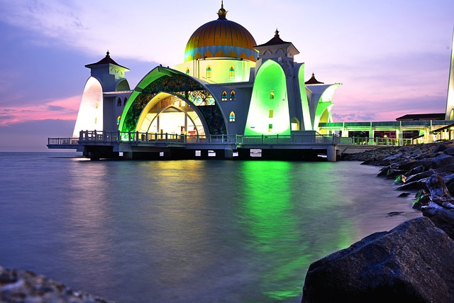 Illuminated Malacca Straits Mosque at dusk, a beautiful example of heritage travel architecture.