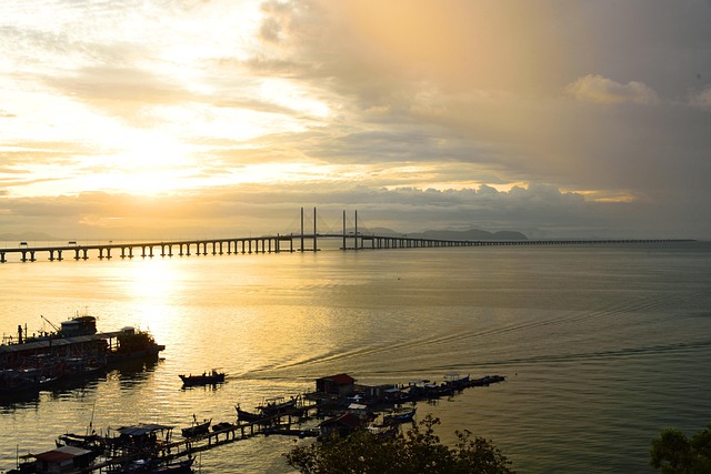 Penang Bridge at sunset with boats in foreground, perfect for heritage travel.