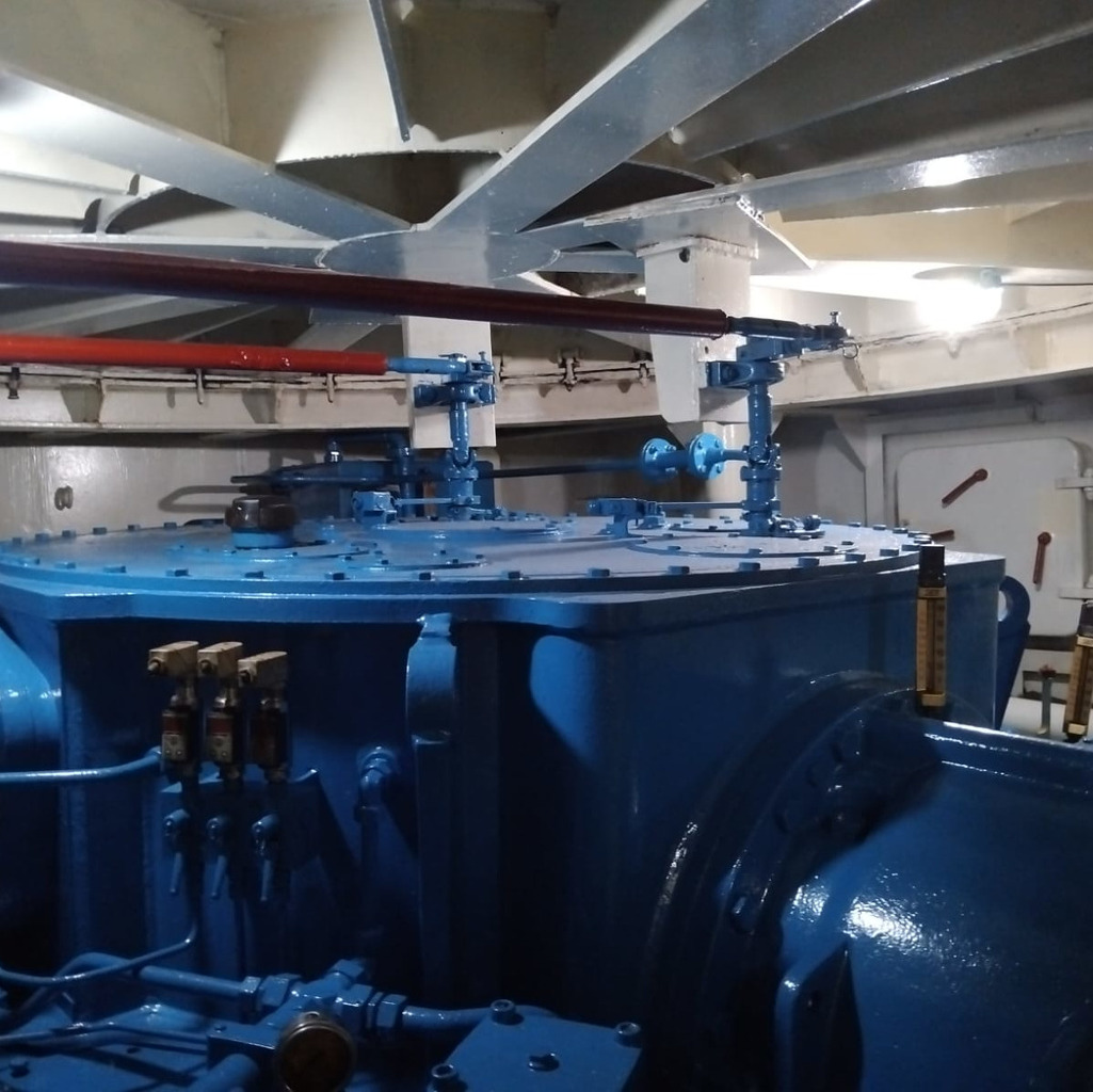 Blue machinery inside the Penang Ferry Museum, with pipes and a white ceiling.